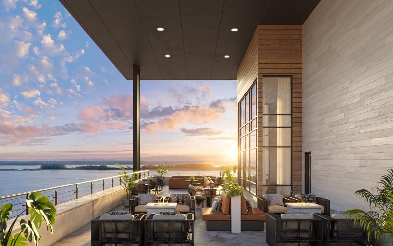 a patio with tables and chairs and a body of water in the background